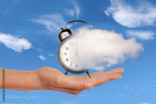 Hand holding a clock dissolving away in a cloud. Time flies, time management concept. Surreal collage. photo