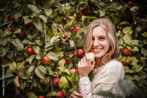 Young woman full of happy energy posing and smiling to camera with an apple in her hand.