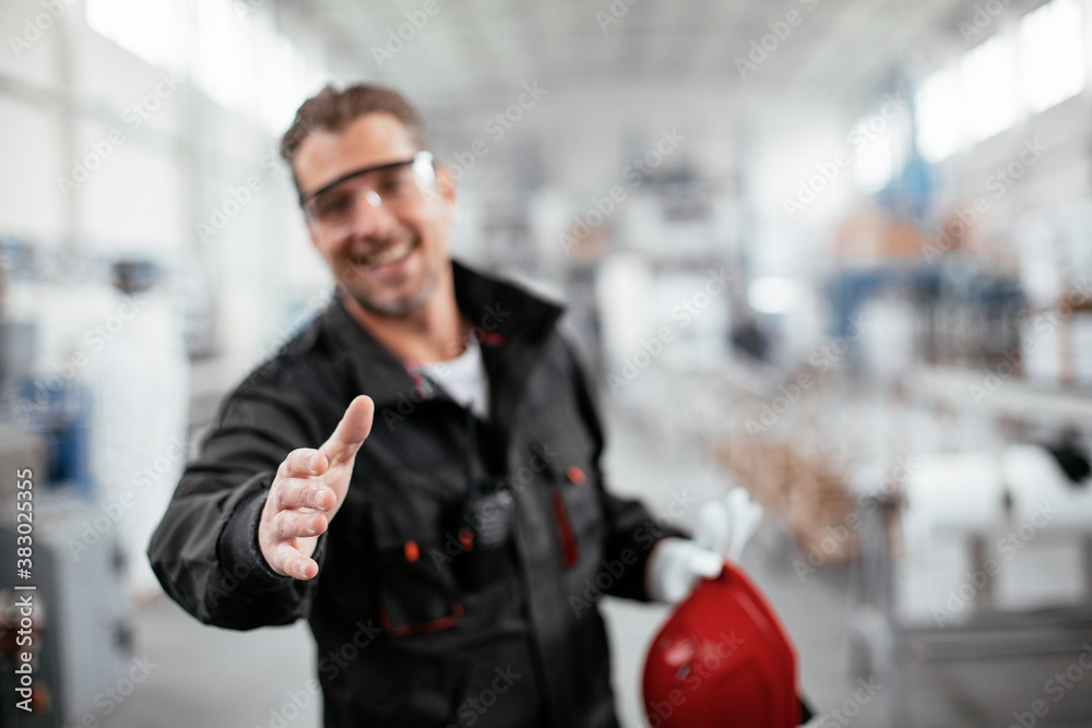 Portrait of factory worker. Man handshake in factory...