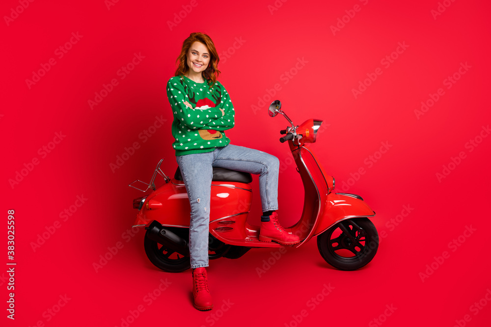 Photo portrait of confident biker sitting on scooter with folded arms wearing ugly green sweater isolated on vivid red colored background