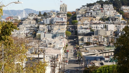 Iconic hilly street and crossroads in San Francisco, Northern California, USA. Steep downhill road and pedestrian walkway. Downtown real estate, victorian townhouses abd other residential buildings