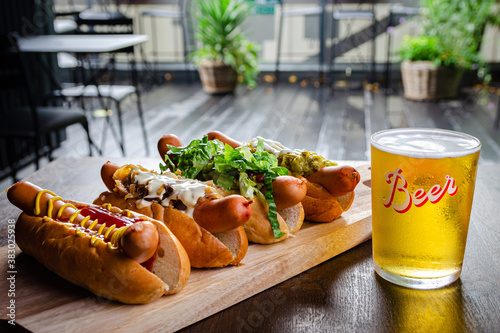 Принти на полотні Four types of delicious hot dogs and beer on a wooden board and brown table view