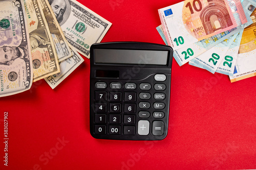 Flat lay or top view of calculator, money dollars and euro on red background