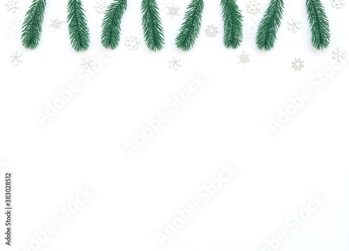 Christmas, New Year or winter white background with fir tree branches, small white snowflakes, beads. Xmas and Happy New Year holiday concept. New Year greeting card. Flat lay, top view, copy space.