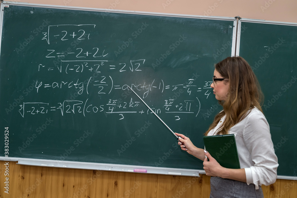 Young teacher writing and explain the mathematical formulas on a chalkboard Young teacher writing and explain the mathematical formulas on a chalkboard