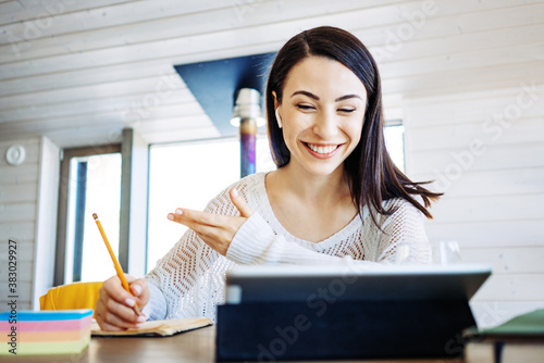 Pretty woman sitting at home and learning remote using tablet computer. Private house workplace
