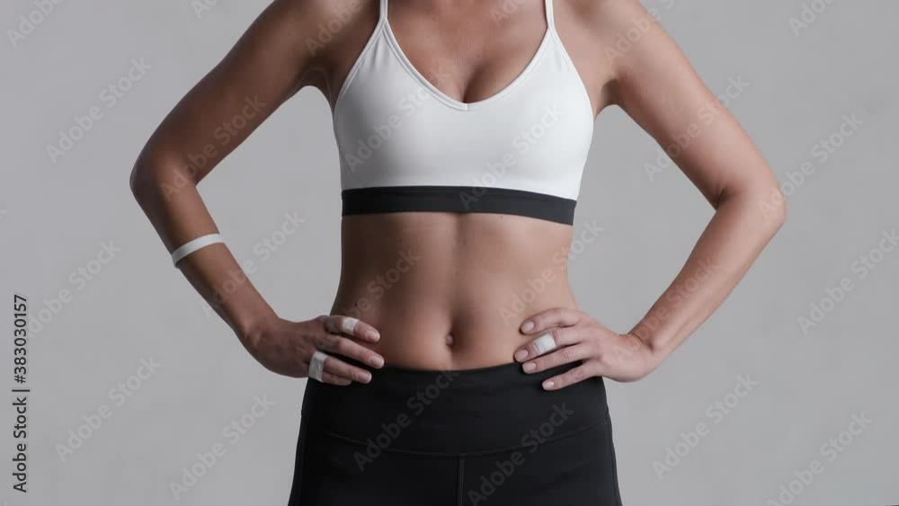 Portrait of beautiful mid adult woman looking at camera isolated on grey background. Proud and fit woman standing on gray wall ready for gym exercise. Strong mixed race girl after cross training. Portrait of beautiful mid adult woman looking at camera isolated on grey background. Proud and fit woman standing on gray wall ready for gym exercise. Strong mixed race girl after cross training.