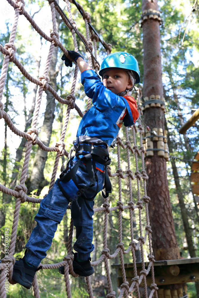 Child overcoming mesh obstacle in forest adventure park