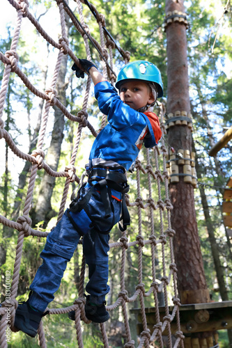 Child overcoming mesh obstacle in forest adventure park
