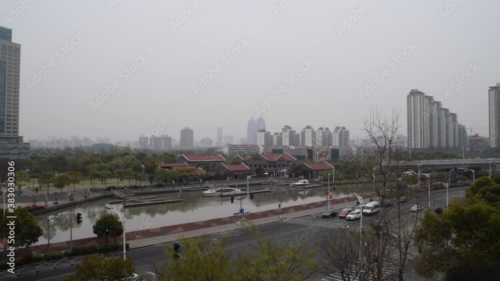 SLOW MOTION: Intersection in Shanghai China on Cloudy Day with car traffic going by and river in Background SLOW MOTION: Intersection in Shanghai China on Cloudy Day with car traffic going by and river in Background