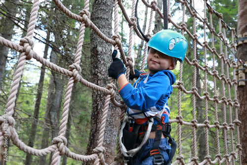Kid overcoming mesh obstacle in forest adventure park