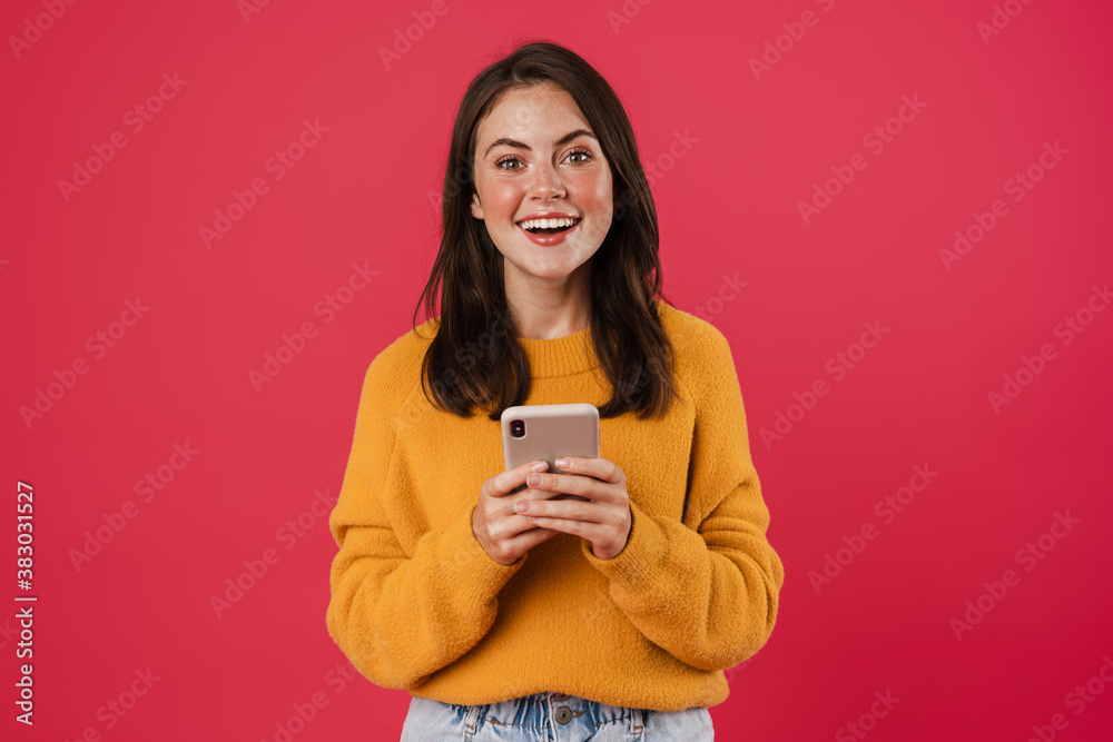 Image of joyful brunette girl smiling and using cellphone Image of joyful brunette girl smiling and using cellphone
