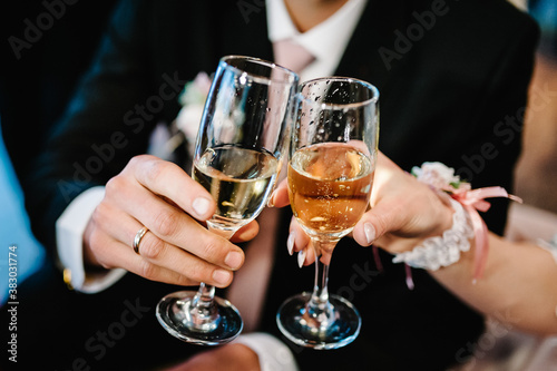 The bride and groom holds a glass of champagne and stand on wedding ceremony. Close up.