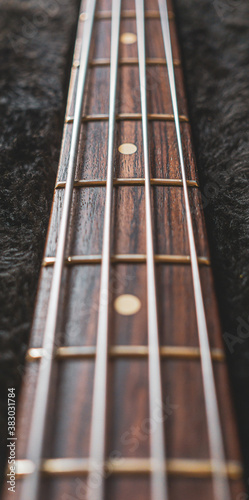 фотографія Neck and fingerboard of a jazz bass guitar with black background.
