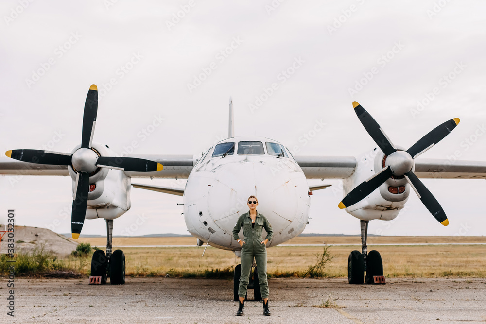 Fototapeta premium Confident woman pilot wearing uniform, standing in front of an airplane.