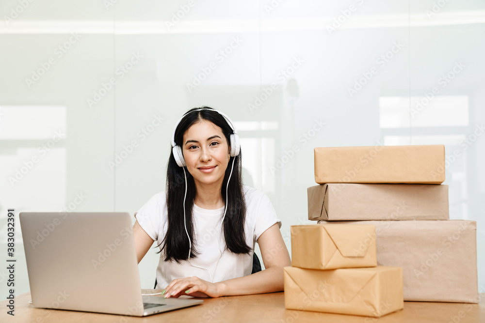 Photo of asian delivery assistance working with packages and laptop Photo of asian delivery assistance working with packages and laptop