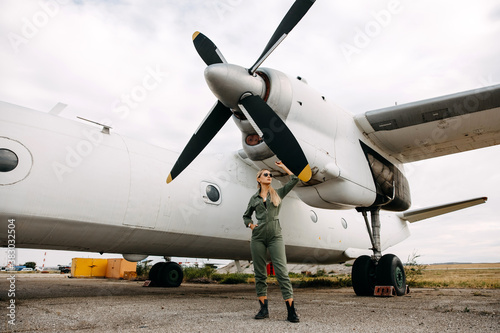 Woman pilot wearing uniform, standing in front of an airplane propeller.