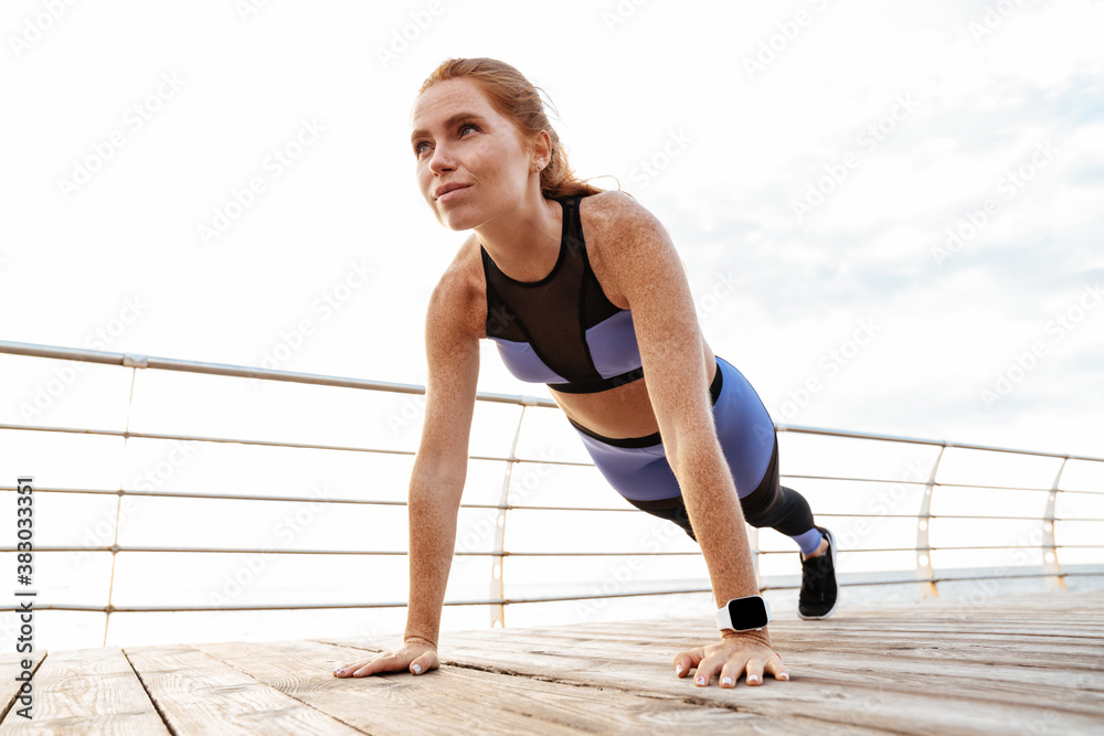 Image of redhead athletic sportswoman doing exercise while working out