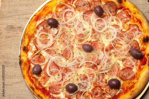Pepperoni pizza with onion rings and black olives on white background. Selective focus