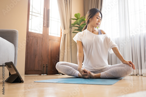 Woman relaxing with yoga at home by following online tutorial.
