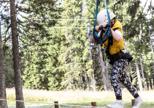 Small boy walking on a rope during canopy tour in nature.