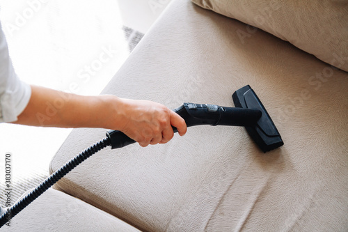 Hand cleaning a sofa with steam cleaner, Home cleaning concept.