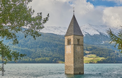 Submerged church tower in the lake reschen in tirol. Lago di Resia with snow covered mountains in the background. photo