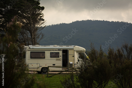 A white motorhome parked in a park among the trees. Horizontal format.