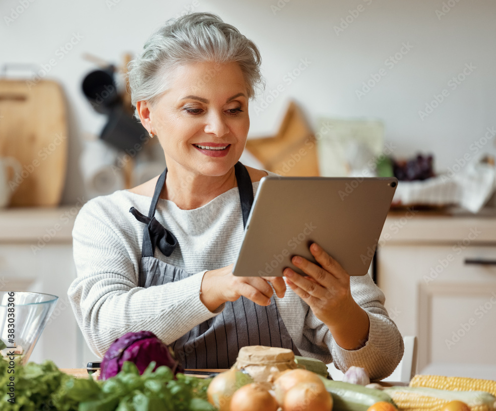 Φωτογραφία Cheerful middle aged housewife in apron pours vegetable oil into a fresh salad a
