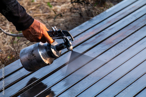 spray painting metal work, steel painters man with a spray gun in hand, laborer or labor day concept, copy space