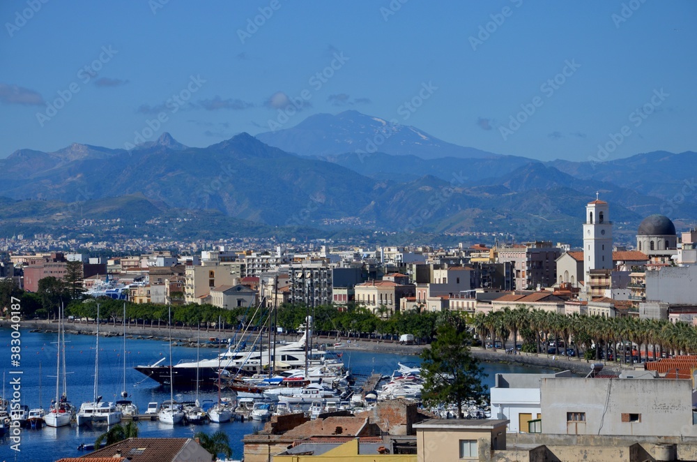 Milazzo in Sicily with view to the port, etna volcano on horizon, blue sky background