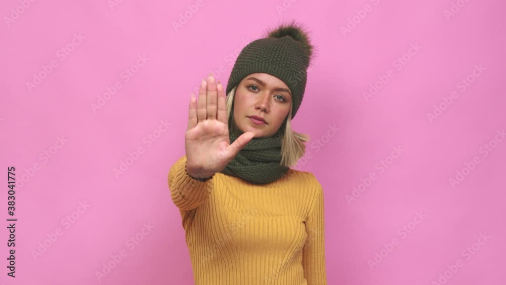 Young cute woman winter clothes standing with outstretched hand showing stop sign, preventing you Young cute woman winter clothes standing with outstretched hand showing stop sign, preventing you
