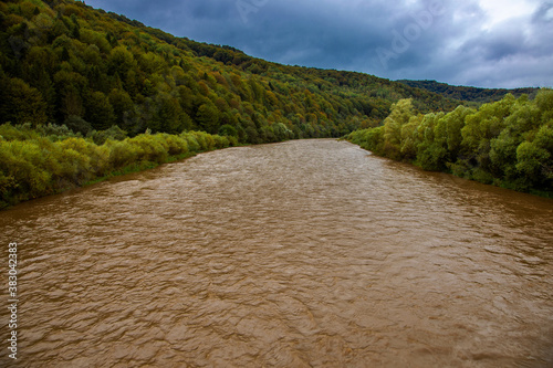 Flood on the mountain river of the Carpathians. Fast current with muddy water on a mountain river. Stryy river in the Carpathians, Ukraine photo