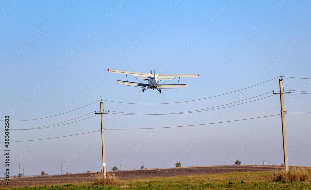 small biplane, an agricultural maize plane, with a special diffuser for field fertilizers and pesticides, picks up speed and takes off over the autumn field. small biplane, an agricultural maize plane, with a special diffuser for field fertilizers and pesticides, picks up speed and takes off over the autumn field.