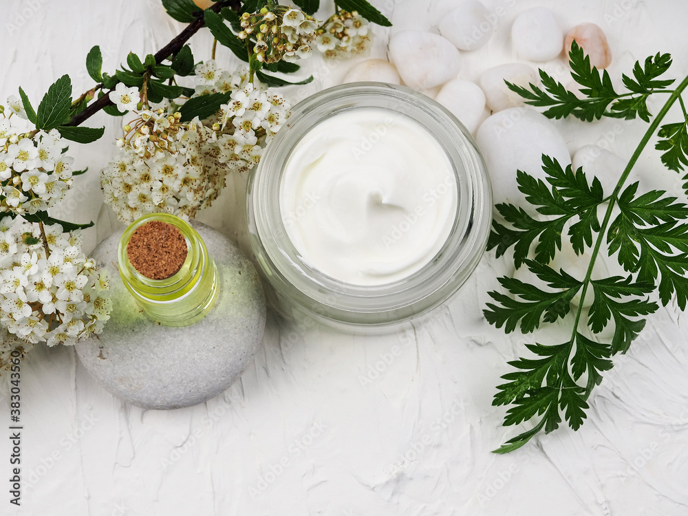 Closeup shot of organic oil and cream. green cosmetic arrangement, Fresh herbal skincare cosmetics. Essential oil, craft bottle, flowers, jar facial cream. Natural beauty care remedy.