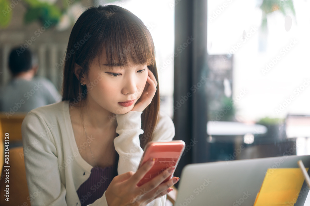 Young adult asian student woman using mobile phone for online application at indoor cafe. Young adult asian student woman using mobile phone for online application at indoor cafe.