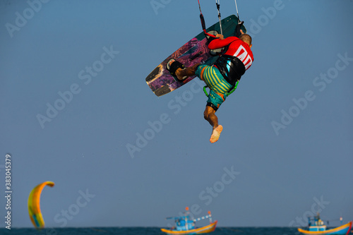 Kitesurfing on the waves of the sea in Mui Ne beach, Phan Thiet, Binh Thuan, Vietnam. Doing the trick - one foot
