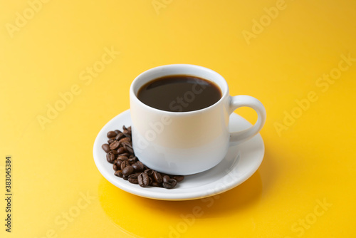 cup of coffee with grains and yellow background © luiz