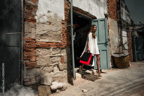 Urban portrait of tired gorgeous Young woman with new brandy things bag clothes in vietnamese slum © Oleg