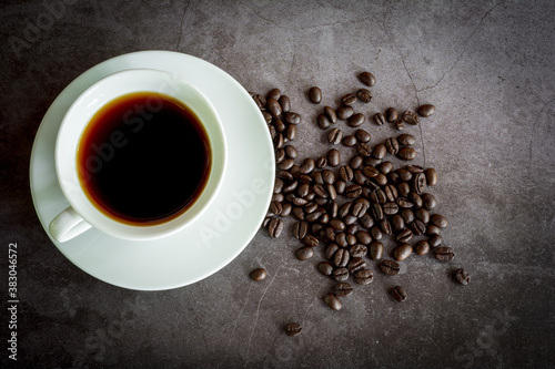 Refresh and energy drink concept. Hot black coffee or espresso in a white ceramic cup and coffee beans on a dark stone table.