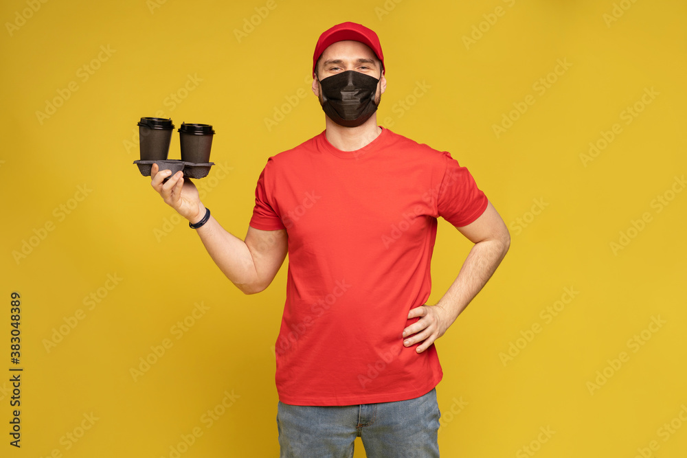 Delivery man in red cap blank t-shirt uniform mask gloves isolated on yellow background studio Guy employee hold takeaway cup of coffee Service quarantine pandemic coronavirus virus 2019-ncov concept. Delivery man in red cap blank t-shirt uniform mask gloves isolated on yellow background studio Guy employee hold takeaway cup of coffee Service quarantine pandemic coronavirus virus 2019-ncov concept.