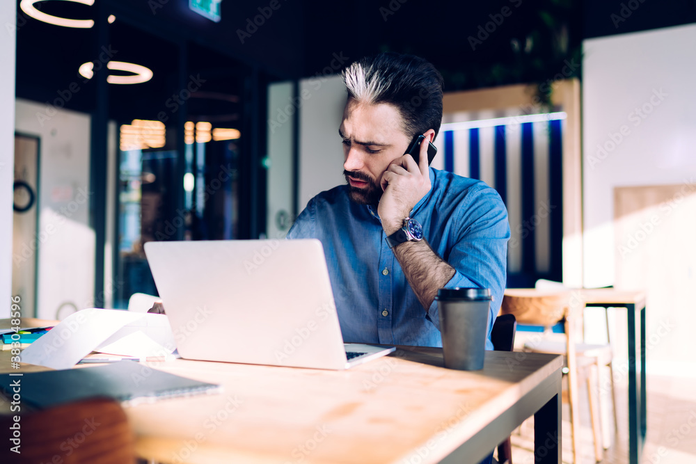 Concentrated man speaking on phone at workplace