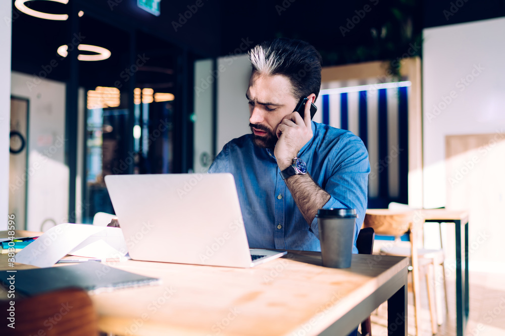Obraz premium Concentrated man speaking on phone at workplace
