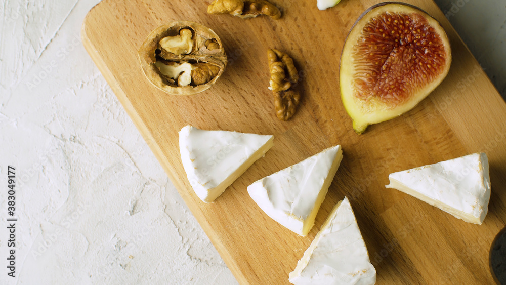 Macro shot camembert, walnuts and halves of fig on a wooden cutting board. Healthy fresh food concept