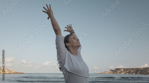 Young woman with outstretched hands doing yoga in early morning on the beach. High quality photo photo