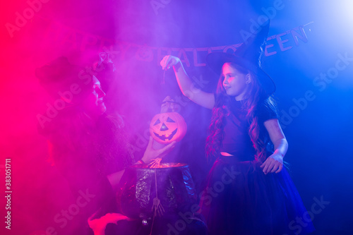 Funny child girl and woman in witches costumes for Halloween with pumpkin Jack.