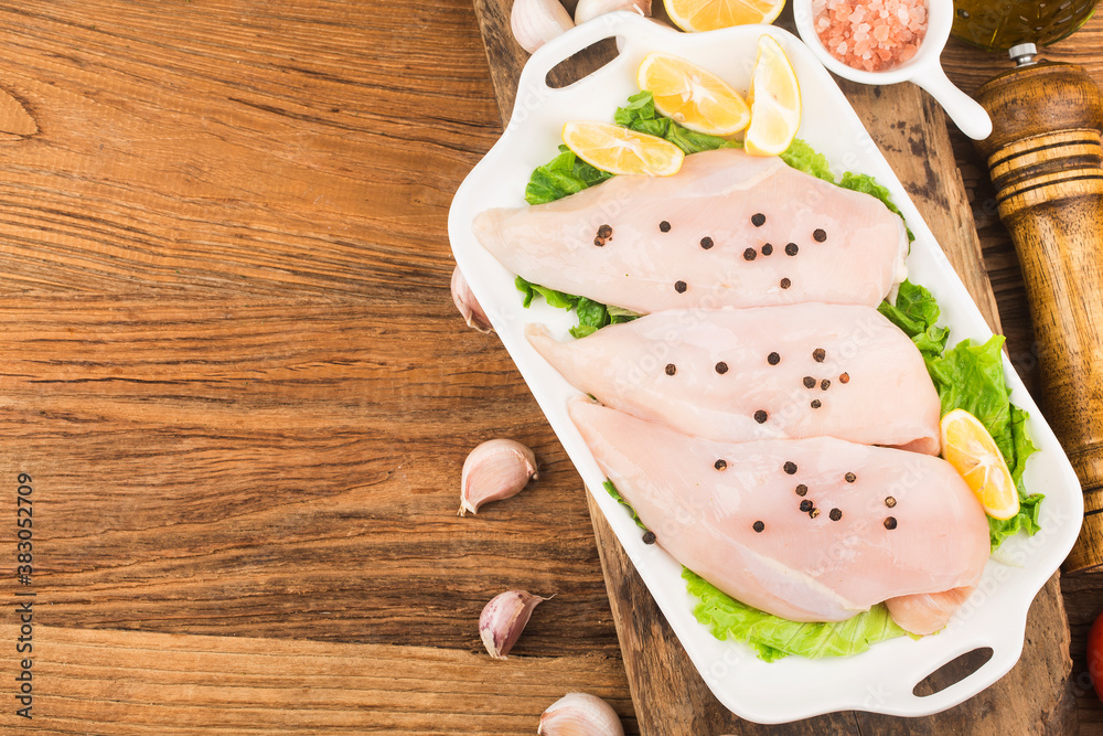 Raw chicken breasts and spices on wooden cutting board, Raw chicken breasts and spices on wooden cutting board,