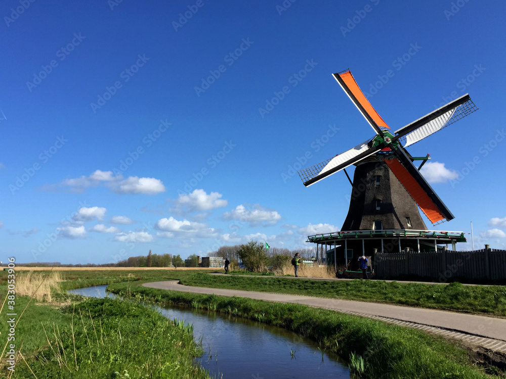 dutch historic windmills on meadow near the river at blue sky, in Zaanse Schans, North Holland, Netherlands