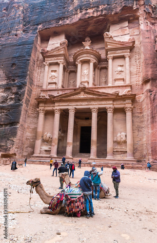 Camels are lying on the ground and are resting and waiting for tourists in the square in front of Al-Khazneh in Petra near Wadi Musa city in Jordan