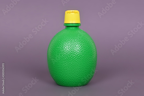 Concentrate lemon juice in a green bottle on a gray background.